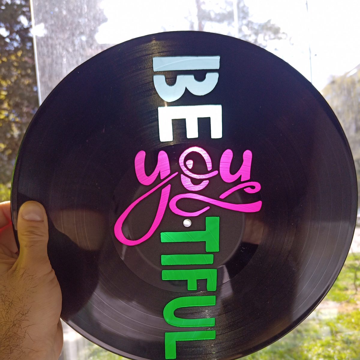 „Be you tiful“ – barevný nápis na desce držené v ruce