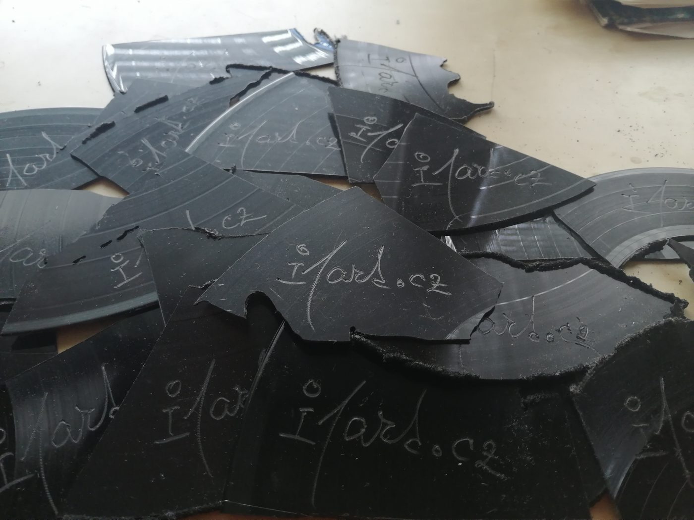 Hromada vizitek vyřezaných z odřezků vinylu s vygravírovanou adresou ateliéru